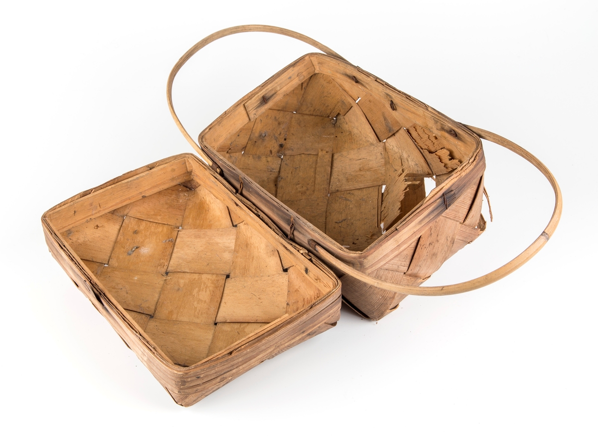 Rektangulær kurv, skråflettet av brede spon. Hengslet lokk, 2 hanker.