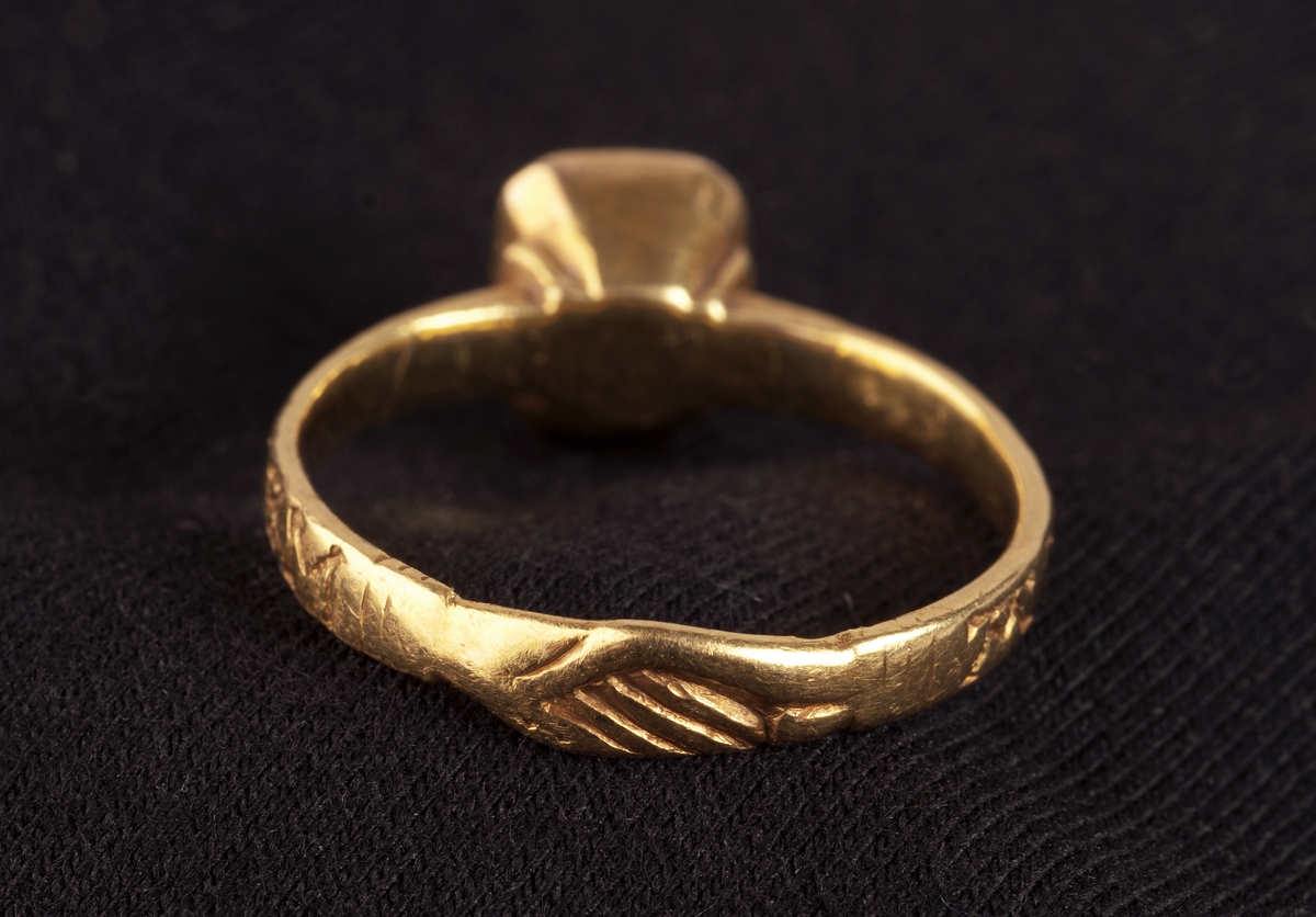 Fingerring av guld med infattad röd sten och handslag på skenans baksida. På ringens utsida ingraverat  AVEM ARIA ( d.v.s. AVE MARIA) och två likarmade kors. Tillhörande etui UM20676b.

Didners lät sätta in den ljusröda rubinen.