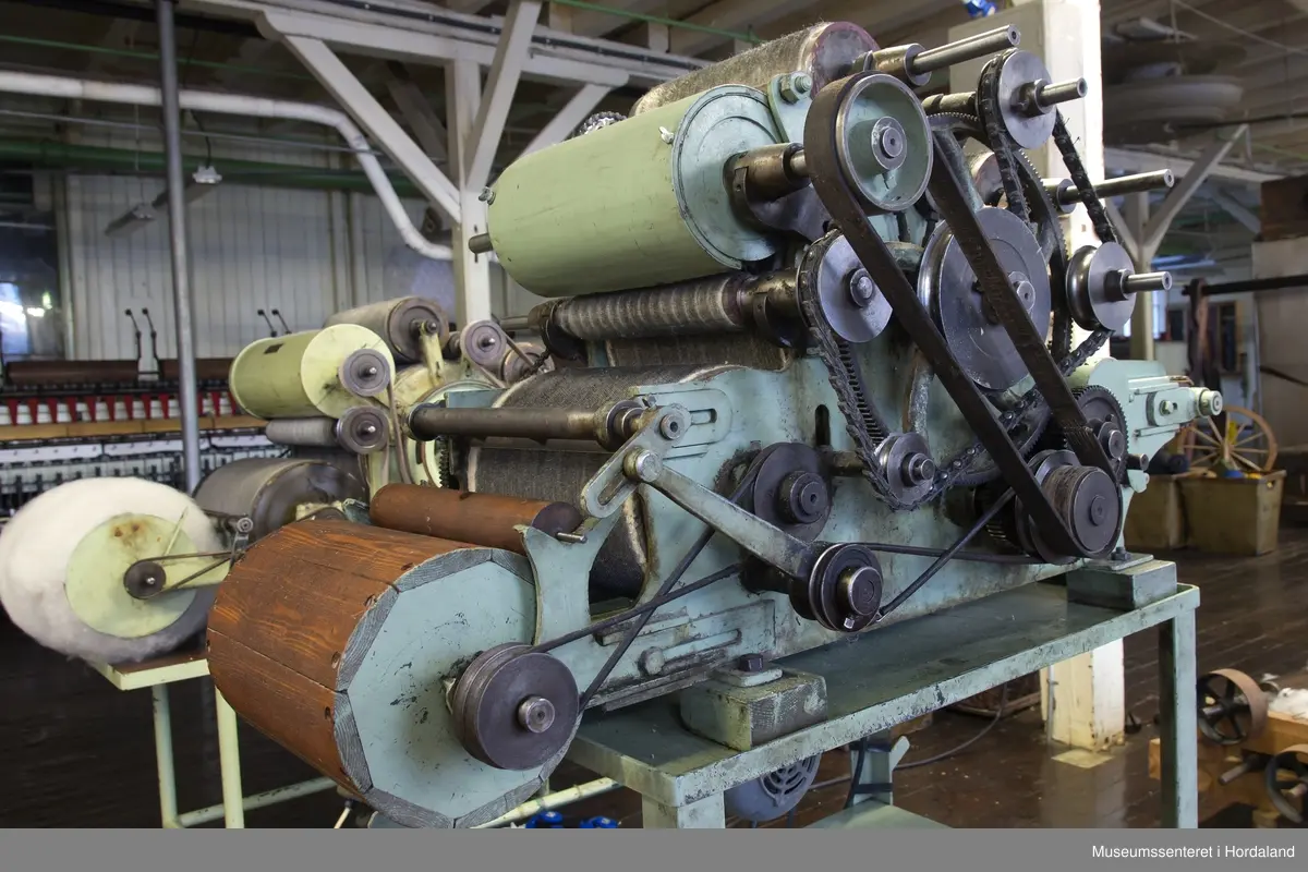 Mintgrøn prøvekardemaskin med tredetaljar, montert på stativ. Ukjend fabrikat.