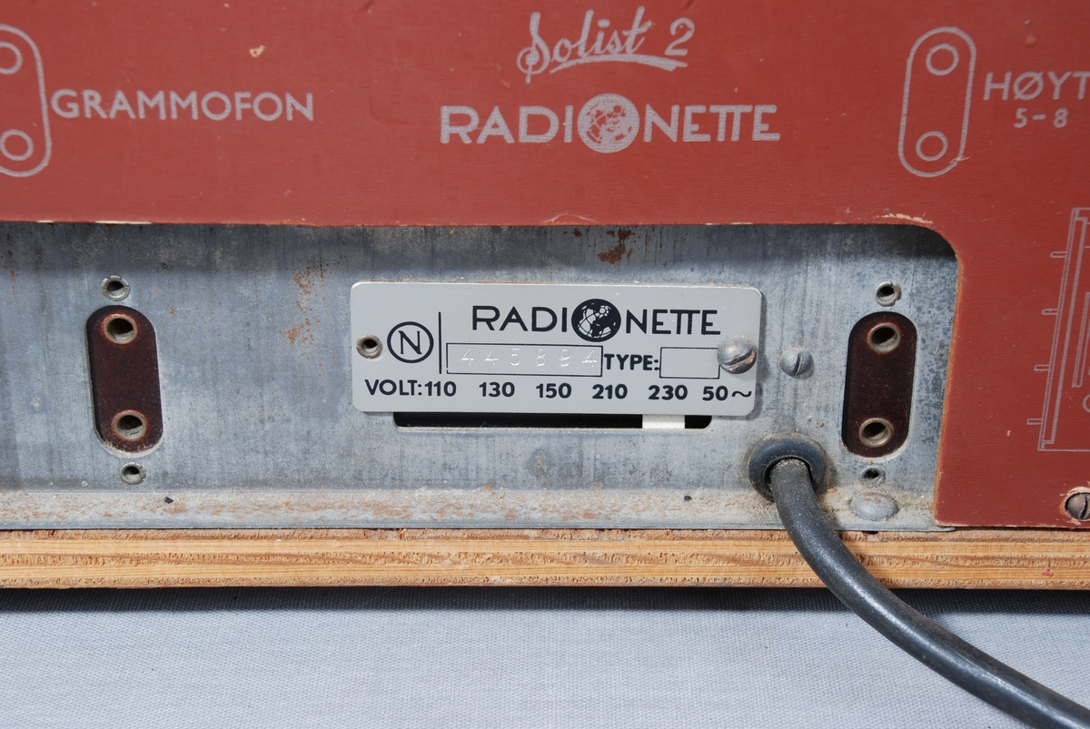 Radiomottaker for kort-/mellom- og langbølgemottak. Rektangulær kasse med åpning for høyttaler dekket av tekstil på framsiden. Ved siden av stasjonsvelger med viser på skala. Knapper for regulering av lydstyrke, lysstyrke, søk og valg av frekvensbånd/grammofon. På baksiden kontakt for antenne, jord og grammofon. Merkelapp for betalt stempelavgift, og skilt med wattstyrke. Tegning av kretskort. Til ledningen er festet en eske med Mullard radiorør. Kabel med støpsel på baksiden