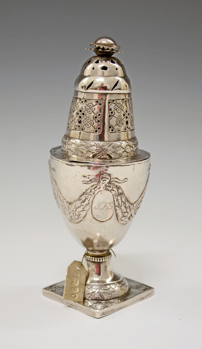 Fra protokollen: Sukkerdrysse av sølv, urne form, Ludvig 16. stil. Stemplet synes at være Kristiansands bystempel.

Oppført som sukkerdrysse i protokollen, men kan det være en "sanddrysse" - for fjerning av overflødig blekk ved bruk av fjærpenn og blekk?