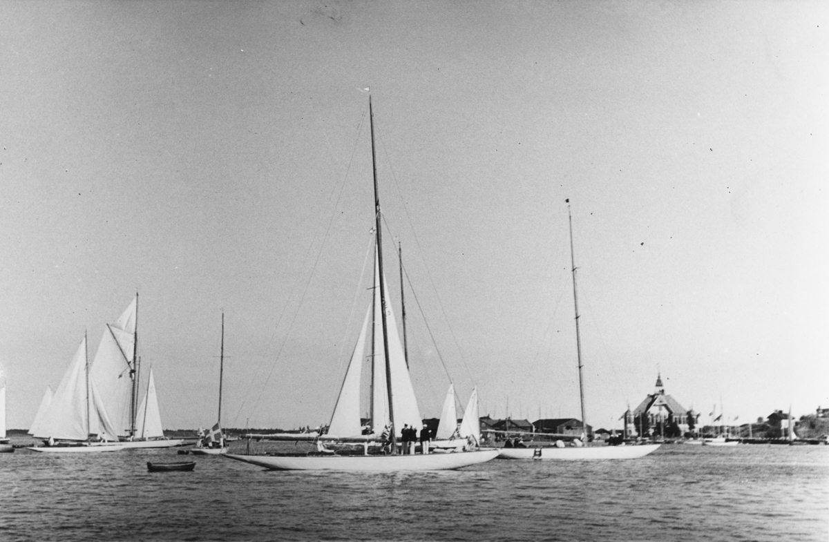 År 1936 företog flera båtar ur KSSS en eskadersegling ("Sjötåget till Helsingfors") för att deltaga i Nyländska Jaktklubbens 75-årsfirande med åtföljande regatta. Bilden är tagen fredagen 9 juli i samband med eskaderns ankomst till Helsingfors. I bakgrunden NJK:s klubbhus på Blekholmen.