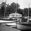 KSSS paviljong på Biskopsudden på Djurgården, uppförd 1930, inrymde sommartid sällskapets sekretariat. Motorjakten med namnet WINDY närmast kameran har inte säkert kunnat identifieras.