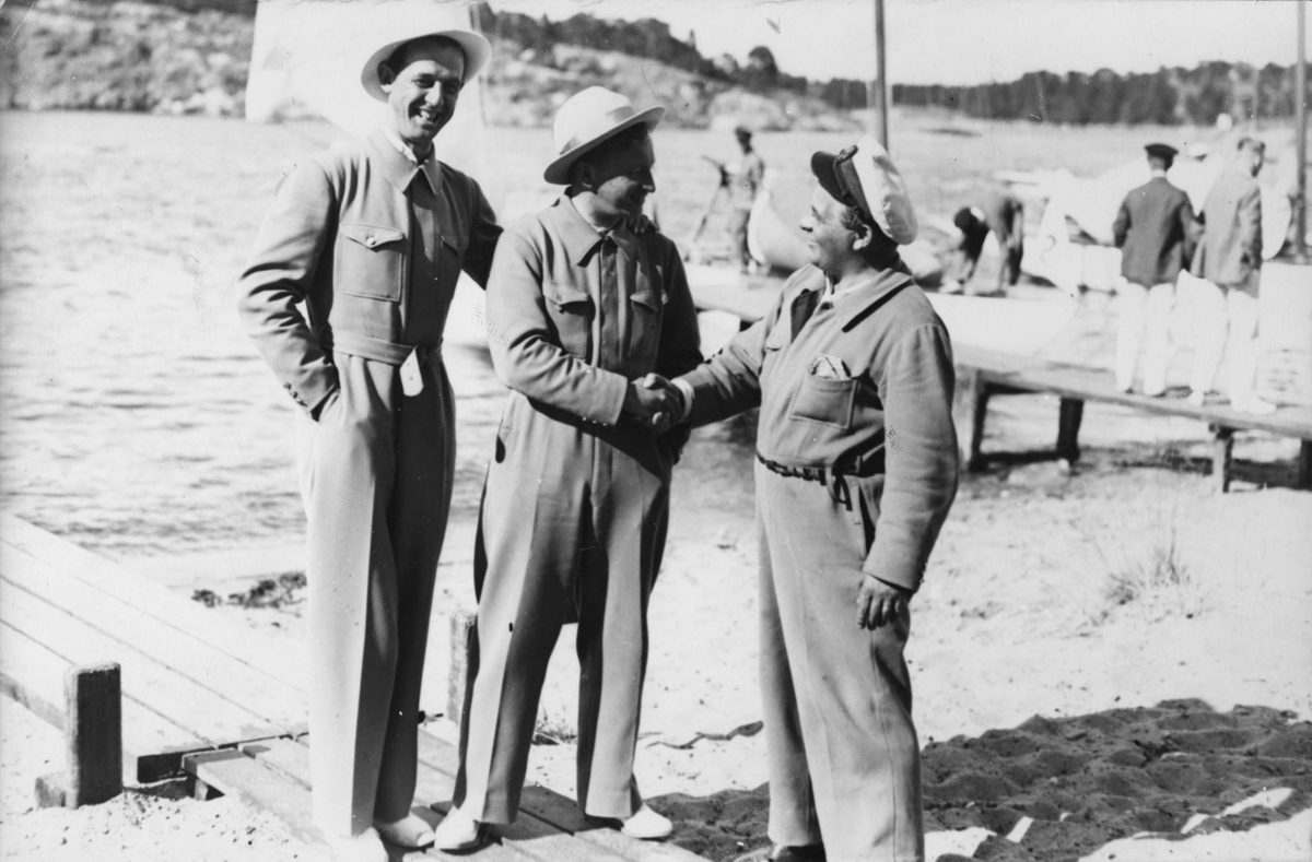 Sandhamn söndagen 6 juli 1930: den svenska båten 6-S31 BISSBI med Sven Salén som rorsman har erövrat Entonnarpokalen. På bilden gratuleras Salén i mitten av Evert Taube t h. Mannen t v är Clarence Hammar, som ingick i besättningen på BISSBI.