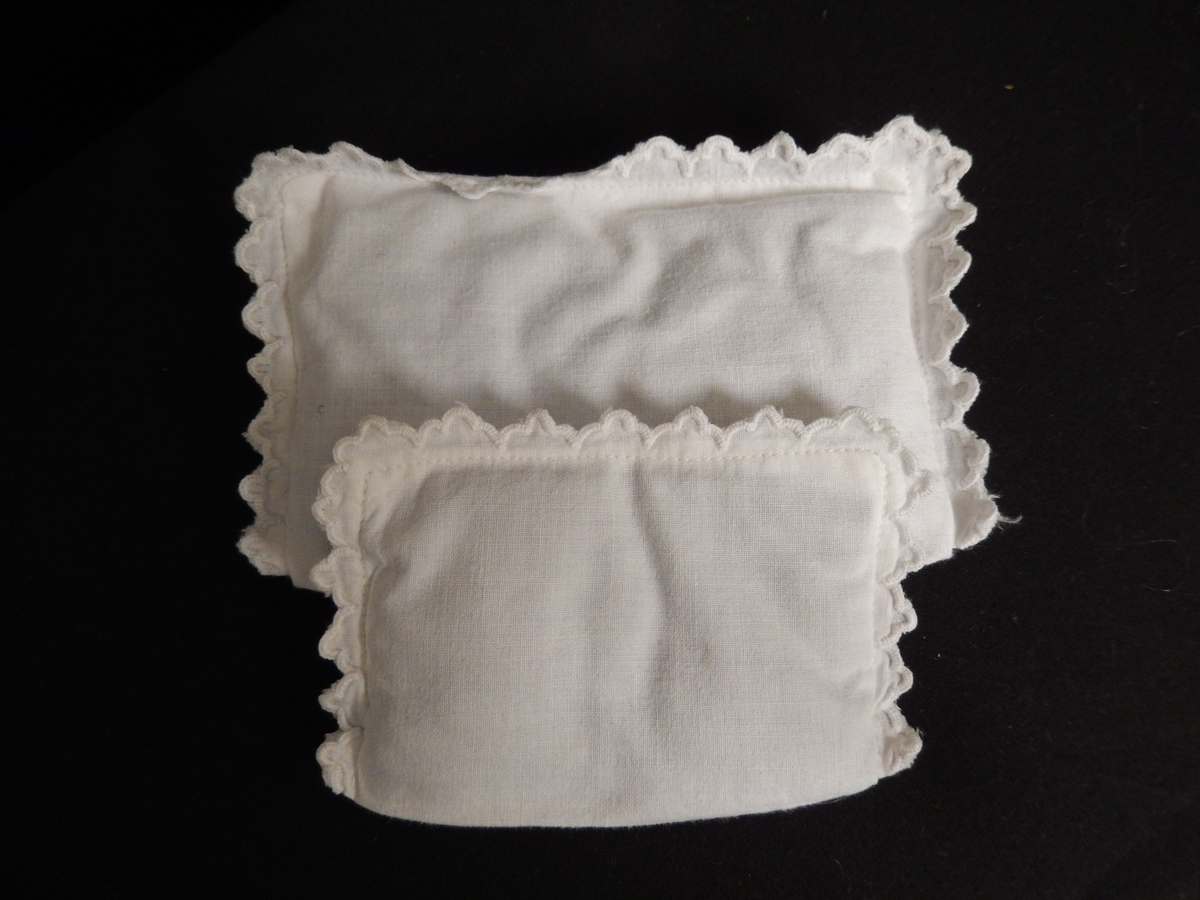 En dokkeseng i kurvfletting fra ca. 1905, med løse sengegavler, en madrass, et laken (glasshånklr med monogram), en overmadrass, to puter, med putevar, en dyne og et heklet sengeteppe.