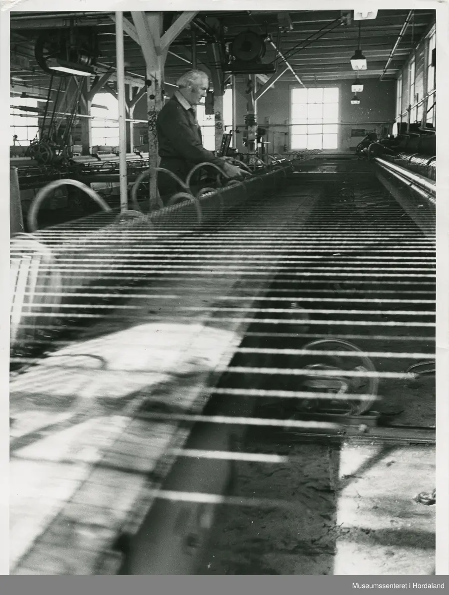 Arbeidsliv ved Salhus Tricotagefabrik i Salhus, Bergen i 1976. Arbeidar ved selfaktor (spinnemaskin) på Salhus Tricotagefabrik.