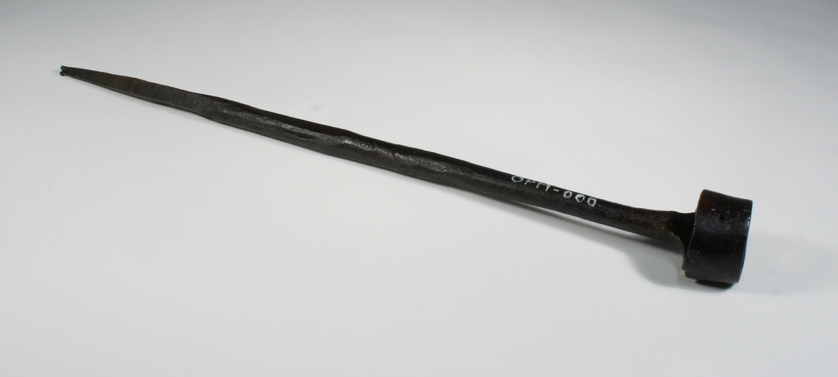 Består, foruten selve brennemerket, av en tange for montering av håndtak. Brennemerket har form som et galgesymbol med en sirkel rundt. Har trolig opprinnelig vært påmontert et trehåndtak som nå er borte.