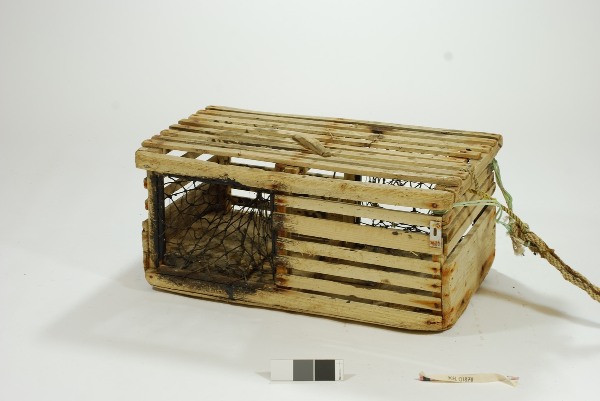Typisk eksempel på kasse-tene, hvor original fiskekasse er benyttet som fangstfelle. Kort og kompakt kasse med bunn av gammel utrangert fiskekasse. Horisontale lekter overfor selve kassebordene. Grovt hjemmelaget garn av nylontau med tverrknuter - et sjeldent fenomen! 
En inngang på hver langside. Ingen fangstkammer. 
Agnpinne av grov metalltråd. 

Kalven: Et tynnere tau er festet til garnet i kalven tversgående, før å gjøre maskene mindre. Kalvene er impregnert med tjære, trolig for å gjøre tauet mørkt slik at hummeren går inn. Kalvene er festet til åpningen med en lekte. Garnet festet rundt en lekte som deretter er spikret fast i tena. Metallringer i kalveåpningene. 

Lokk av to lekter. Lukkeåpning; moderne skyvepatent med vrider. Skyvemekanisme; skyves bort og vippes opp. 
En liten metallplate er festet vertikalt over to lekter, - uvisst hvorfor. Støpt betonghelle i hver ende, dekker hele bredden. E.V. risset inn i den ene. 

Komplett tauverk med væler. Tau i naturfiber. Festet til tena med syntetisk tau. Ekstra tau flettet inn i nederste del for å gi tauet flytekapasitet. 
Væle: malt hvit med en rød stripe ca. 10 cm fra bunnen. Bunnplata malt rød. E.V. skåret inn i treverket på det hvite feltet. Spiss ende med hull til tau. 
Tolver og sekser væler: 1) 4 korkbiter. Festet til tauet med blått syntetisk tau. Malt helt hvit, men rød i bunnen. 2) 6 korkbiter. Hvitmalte, rød i enden. Festet til tau med tau i naturfiber.