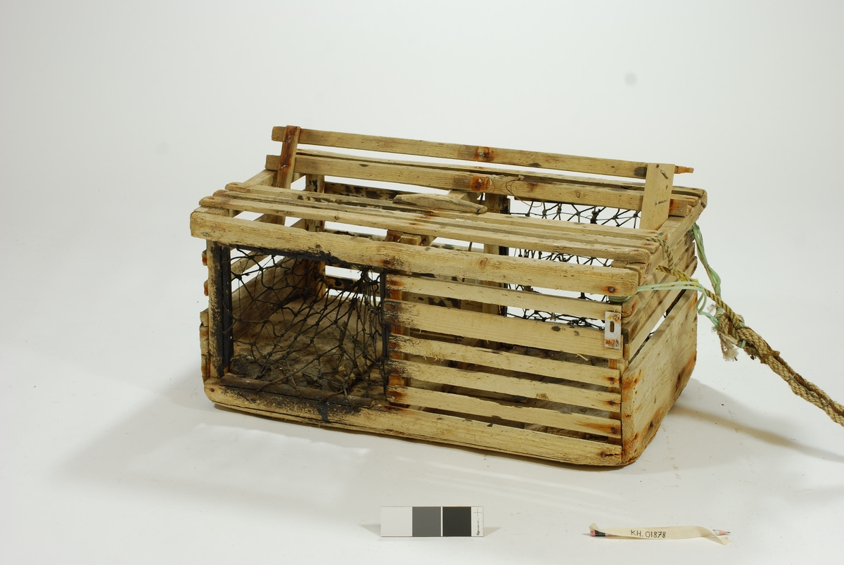 Typisk eksempel på kasse-tene, hvor original fiskekasse er benyttet som fangstfelle. Kort og kompakt kasse med bunn av gammel utrangert fiskekasse. Horisontale lekter overfor selve kassebordene. Grovt hjemmelaget garn av nylontau med tverrknuter - et sjeldent fenomen! 
En inngang på hver langside. Ingen fangstkammer. 
Agnpinne av grov metalltråd. 

Kalven: Et tynnere tau er festet til garnet i kalven tversgående, før å gjøre maskene mindre. Kalvene er impregnert med tjære, trolig for å gjøre tauet mørkt slik at hummeren går inn. Kalvene er festet til åpningen med en lekte. Garnet festet rundt en lekte som deretter er spikret fast i tena. Metallringer i kalveåpningene. 

Lokk av to lekter. Lukkeåpning; moderne skyvepatent med vrider. Skyvemekanisme; skyves bort og vippes opp. 
En liten metallplate er festet vertikalt over to lekter, - uvisst hvorfor. Støpt betonghelle i hver ende, dekker hele bredden. E.V. risset inn i den ene. 

Komplett tauverk med væler. Tau i naturfiber. Festet til tena med syntetisk tau. Ekstra tau flettet inn i nederste del for å gi tauet flytekapasitet. 
Væle: malt hvit med en rød stripe ca. 10 cm fra bunnen. Bunnplata malt rød. E.V. skåret inn i treverket på det hvite feltet. Spiss ende med hull til tau. 
Tolver og sekser væler: 1) 4 korkbiter. Festet til tauet med blått syntetisk tau. Malt helt hvit, men rød i bunnen. 2) 6 korkbiter. Hvitmalte, rød i enden. Festet til tau med tau i naturfiber.