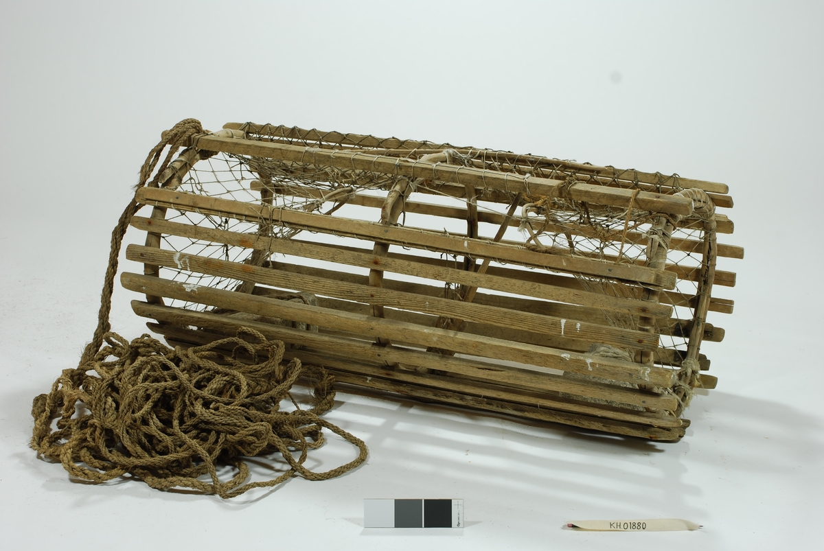 Moderat stor sylindrisk tene med inngang i begge ender. Lekter i ulike dimensjoner. Gjorderinger av ener.  Midterste gjordering sprukket. Kalveringer av ener. Kalver i hvitt garn. Reparasjoner i begge kalvene. Garnbusen på toppen i et litt kraftigere tau. Slitt av flere steder. Reparasjoner/fester med gresstau og hvitt tau (kokos?). 
Lukkeåpning i garn med håndsnittet trepinne. Agnspyd i tre. Festet til midterste gjordering med gresstau. Synkestener av granitt, en i hver ende. Den ene festet med hvitt tau (kokos?), den andre med et tykkere gresstau. Har ikke gummi/deler av regntøy til beskyttelse som en rekke andre tener har. Bunnsvillene/lektene forsterket for stabilitet ved bunn-leie. Langt gresstau festet til. Uten væler.