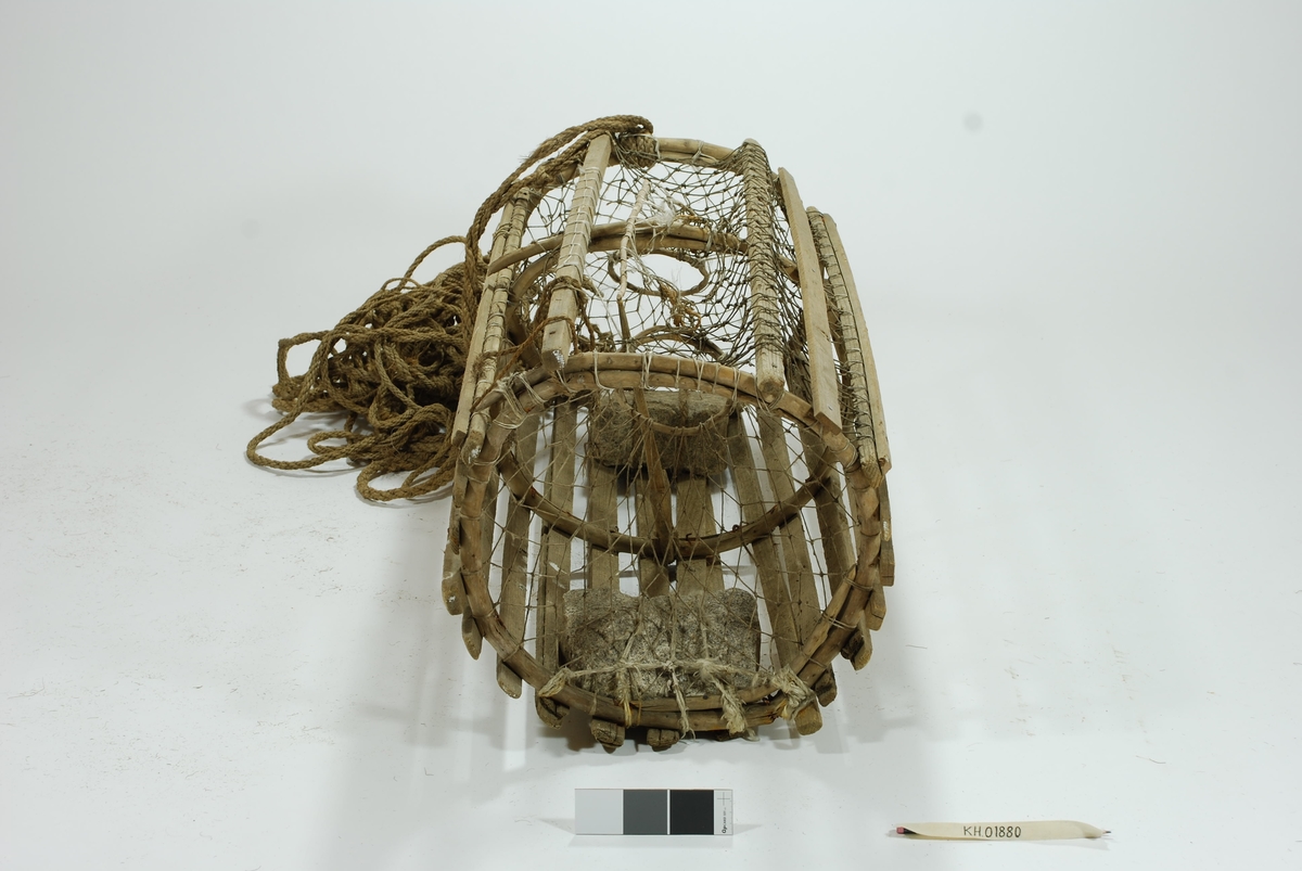 Moderat stor sylindrisk tene med inngang i begge ender. Lekter i ulike dimensjoner. Gjorderinger av ener.  Midterste gjordering sprukket. Kalveringer av ener. Kalver i hvitt garn. Reparasjoner i begge kalvene. Garnbusen på toppen i et litt kraftigere tau. Slitt av flere steder. Reparasjoner/fester med gresstau og hvitt tau (kokos?). 
Lukkeåpning i garn med håndsnittet trepinne. Agnspyd i tre. Festet til midterste gjordering med gresstau. Synkestener av granitt, en i hver ende. Den ene festet med hvitt tau (kokos?), den andre med et tykkere gresstau. Har ikke gummi/deler av regntøy til beskyttelse som en rekke andre tener har. Bunnsvillene/lektene forsterket for stabilitet ved bunn-leie. Langt gresstau festet til. Uten væler.