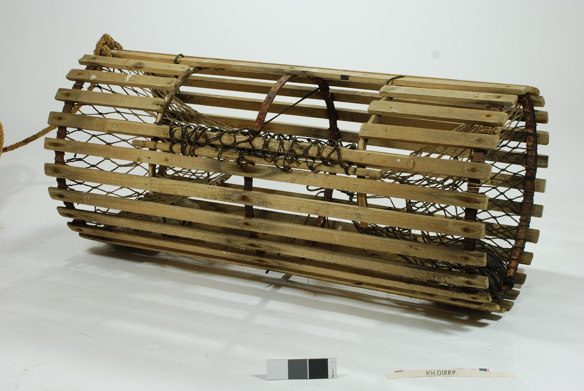 Rund/ sylindrisk sprøtt-tene. Hjemmespunnet garn med store masker. To motstående innganger i kortsidene. Intet fangstkammer. Kalveringer i metall, ovale i formen tilpasset krabbens fasong. Ovalformet åpning i toppen forsterket med ubehandlede barkkledde enerkvister som er formet til. Metallgjorder virker solide og kan være spesiallaget. Agnspyd i metall horisontalt plassert med ekstra sperre i kalveringen. Synkestener i granitt i hver ende, bundet fast med sort tauverk. Åpning med gammeldags lukkepatent med garn og håndspikket pinne. Tena bærer preg av tidligere å ha vært tjæret/ barket. 

Store mengder gresstau og fem væler, tre stk. i treverk og to stk. av kork. 
Hvitmalte trevæler i tre størrelser:
Størst: 63x9 cm.
Mellomst: 51x9 cm. 
Minst: 41x9 cm.
Alle har profilerte kanter og er hvitmalte med sort ende (tjæret). Malingen er nesten slitt av. K.V er skåret inn i de tre fløtene.
Korkvæler:
Lengde: 22cm
Omkrets 32 cm.
K.V risset inn i den ene.