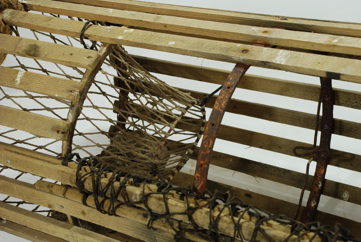 Rund/ sylindrisk sprøtt-tene. Hjemmespunnet garn med store masker. To motstående innganger i kortsidene. Intet fangstkammer. Kalveringer i metall, ovale i formen tilpasset krabbens fasong. Ovalformet åpning i toppen forsterket med ubehandlede barkkledde enerkvister som er formet til. Metallgjorder virker solide og kan være spesiallaget. Agnspyd i metall horisontalt plassert med ekstra sperre i kalveringen. Synkestener i granitt i hver ende, bundet fast med sort tauverk. Åpning med gammeldags lukkepatent med garn og håndspikket pinne. Tena bærer preg av tidligere å ha vært tjæret/ barket. 

Store mengder gresstau og fem væler, tre stk. i treverk og to stk. av kork. 
Hvitmalte trevæler i tre størrelser:
Størst: 63x9 cm.
Mellomst: 51x9 cm. 
Minst: 41x9 cm.
Alle har profilerte kanter og er hvitmalte med sort ende (tjæret). Malingen er nesten slitt av. K.V er skåret inn i de tre fløtene.
Korkvæler:
Lengde: 22cm
Omkrets 32 cm.
K.V risset inn i den ene.