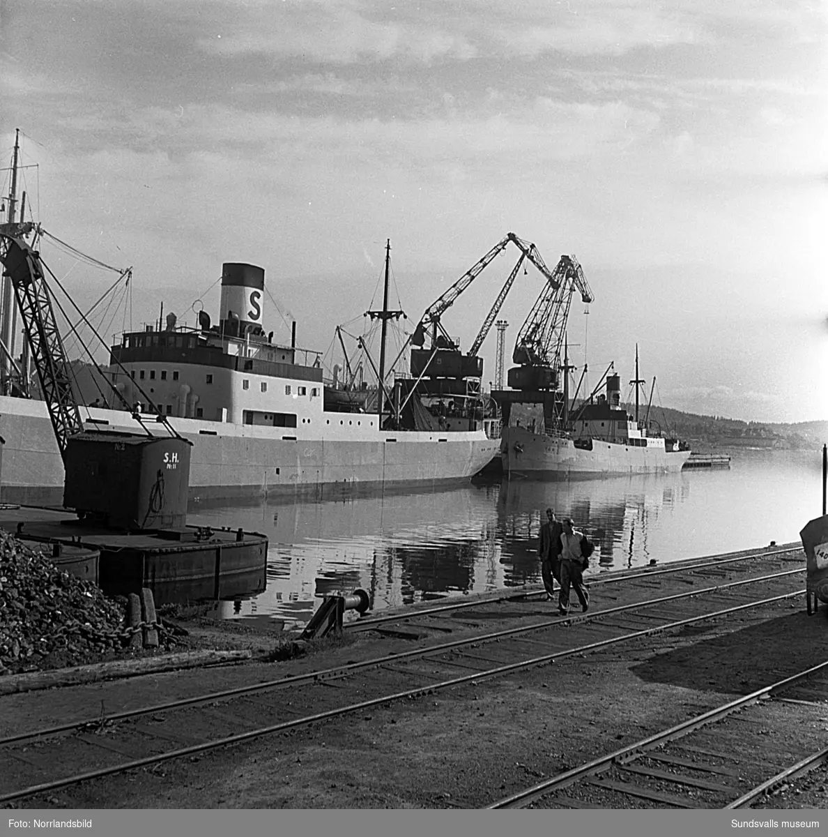 En serie bilder från verksamheten i hamnen i början av 1950-talet. Båtar, pråmar, kranar, kolhögar och magasin.