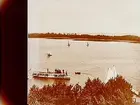 Ångslupen Hemfjärden vid Hjälmarbadens brygga, fem segelbåtar och en roddbåt. Ässön i bakgrunden.
Stereofotografi.