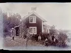 Sommarstugan Fridensborg, envånings sommarstuga med inredd vind och veranda åt vänster. Fem barn och två vuxna vid stugans gavel.
Fotograf Sam Lindskog