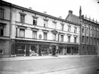 Trevånings stenhus med affärslokaler i gatuplanet. D.J. Elgérus Fabrik & Handels AB. Örebro Installationsbyrå. John Lundmark manufaktur & kappmagasin.