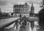 Gamla Vasabron i trä. Nikolaikyrkan. Till höger Telegraf- och Posthuset under byggnad.
Reproduktion 1939, efter en äldre bild från 1910-talet.