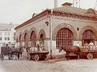 Hallsbergs Mejeri, envånings mejeribyggnad i tegel.
Tre hästskjutsar framför mejeriet, 6 personer.
1 st täkt hästvagn med kusk.