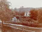 En och en halvvånings bostadshus med glasad veranda. En man med vattenslang.
Grosshandlare Uno Bergvall