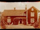 En och en halvvånings bostadshus med förstubro. Grupp 7 personer framför huset.
Anders Nilsson