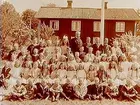 Tysslinge skola, tvåvånings skolbyggnad i bakgrunden.
61 skolbarn och folkskollärare Axel Holmberg.