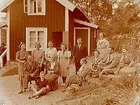 Sommarstugan, grupp 13 personer framför stugan.
Sam Lindskogs familjebild.
