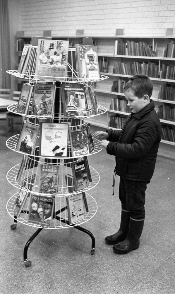 Bibliotek i Pålsboda 10 februari 1967

En pojke i jacka och gummistövlar står vid en ställning med böcker och tittar på böcker.