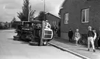 Sopbil välte, 27 juli 1965

En sopbil har vält och ligger på sidan på en gata nära trottoaren. En folksamling har uppstått invid den.