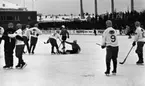 Hot rod, Kungälv - Örebro, 7 januari 1966

På bilden syns bandyspelare i isrinken. En spelare har ramlat och får hjälp av en annan spelare att ta sig upp igen. Reklamskyltar som 'Pripps', 'Zingo' m.m.  syns i bakgrunden. Publik står på läktaren i bakgrunden.