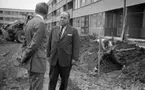 Mosåsflicka, Brandkårsuppvisning, Harar, Transportkillar 27 maj 1967

Två herrar i kostymer, skjortor och slipsar står och samtalar på området där universitet håller på att byggas. I bakgrunden syns en man som är klädd i skjorta, byxor och stövlar som är arbetare och håller på att hugga med ett spett i jorden. En traktor syns även till vänster i bakgrunden.