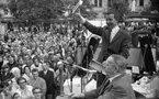 Marknadsafton 16 juni 1967

Under en marknadsafton i centrala Örebro pågår en auktion på gatan. En man sitter på en stol på en scen och håller en auktionsklubba i handen. En annan man står upp och visar ett litet leksakpiano som han håller i höger hand för publiken som står nedanför scenen.