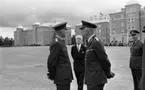 Kungen I3 28 augusti 1967

Kung Gustav VI Adolf besöker Örebro Livregementes Grenadjärer i Grenadjärsstaden. Ett antal män står uppställlda på regementsgården klädda i militäruniformer liksom kungen. Den sistnämnde står och samtalar med en general. En man i svart kostym, vit skjorta och ljus slips syns i bakgrunden.