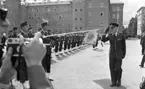 Kungen I3 28 augusti 1967

Kung Gustav VI Adolf besöker Örebro Livregementes Grenadjärer i Grenadjärsstaden. Han passerar förbi en rad uppställda militärer på linje och som skyldrar gevär. Han gör honnör mot dem. En militär med en fana och befälsbricka om halsen syns till vänster. En fotograf tar bilder med en kamera i förgrunden.