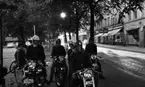 Knuttarna har bil 24 juli 1967

Nära järntorget befinner sig ett ungdomsgäng. Några sitter på
motorcyklar. Det är fyra tonårspojkar och en av dem har en tonårsflicka som sitter bakom honom på motorcykeln. Två andra flickor står bredvid dem till vänster. De som åker motorcyklar har hjälmar på huvudena och tre stycken har också vindskyddsglasögon till hjälmarna.