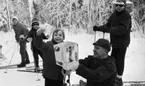 Ånnaboda, fotojobb (?), arbetarkommun 70 år 12 februari 1968

Affärsmannen Totta som äger affären Tottas sport står på knä framför en liten pojke i sjuårsåldern med en vit låda i sina händer. På lådan står det: 