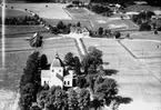 Flygfoto över Ervalla kyrka, bostadshus och byggnader.