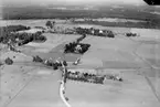 Flygfoto över Ervalla, kyrkan, bostadshus och ekonomibyggnader.
Bilden tagen för vykort.
Förlag: F. L. Carlsson, Ervalla.