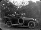 Sex personer i en bild.
Bostadshus. 
Bilen på bilden är en Overland från ca 1913-1914.