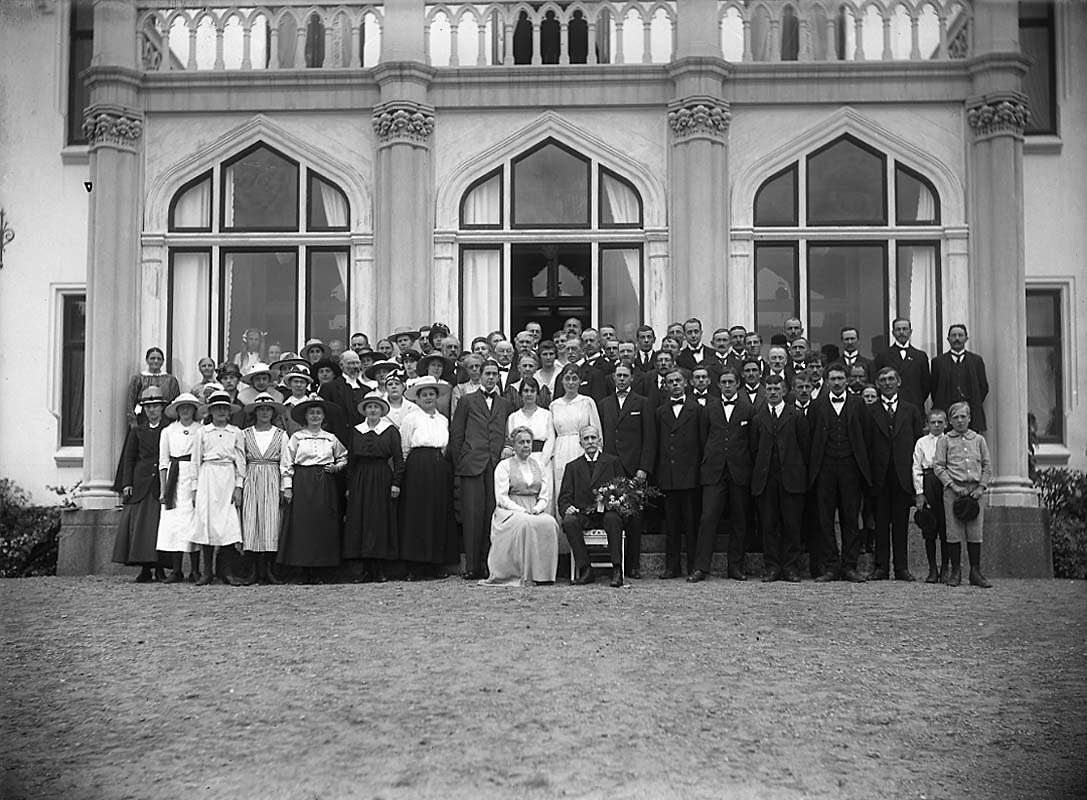 Ett stort gruppfoto vid Boo slot. Längst fram sitter Hugo Hamilton med blombukett, bredvid hustrun Ebba Hamilton. Bakom dem står sönerna Carl Hamilton och Hugo Hamilton, med sina fruar Märta Hamilton, respektive Greta Hamilton.