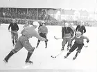 Bandy. 
AIK målvakten tar bollen med en hand framför Olle Sääv.