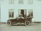 Bil framför Åsby Gård. 
Bilen är en Oldsmobile modell 30 från 1923-24 med en 42 hästkrafters sexcylindrig motor. Den registrerades den 2:e april 1924 på fröken Jenny Larsson, Örebro, och fick registreringsnummer T99. År 1930 ägdes den fortfarande av Jenny Larsson.