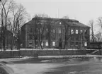 Karolinska läroverket, skolbyggnad i tre våningar.
Svartån i förgrunden.