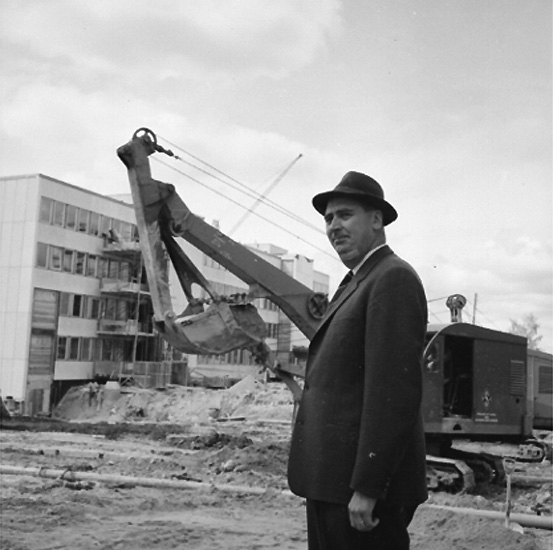 En man. 
Byggnadsarbete i bakgrunden.
Mannen på bilden är civilingenjör Karl-Elis Bowin som arbetade på AB Armerad Betong. Bygget av Stadsbyggnadshus 1 med adress Åbylundsgatan 8A Örebro.