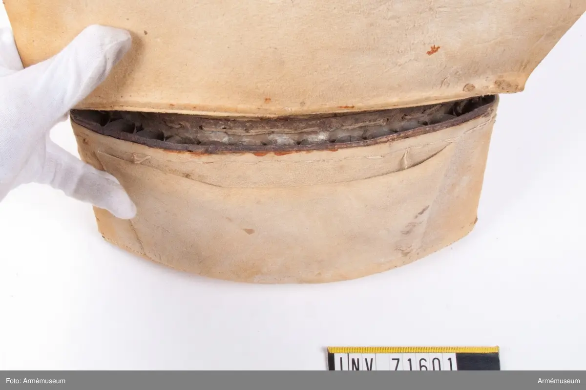 På insidan, under locket finns en ficka. Insatsen är gjord av bleckplåt med plats för 13 patroner med 18 mm kailber.