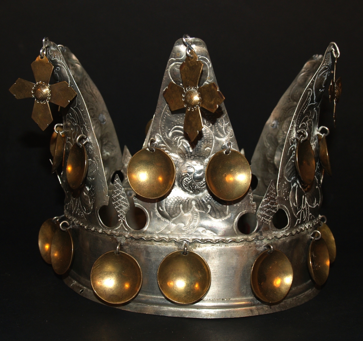 Det er ei heilrend krone, det vil seie at den er klipt/sagd ut av ei metallplate og lodda saman. Den har seks taggar og er ei open krone. Kvar tagg er dekorerte med blomemønster og i toppen er det eit ansikt, som kan tolkast som annankvar mann og kvinne. I kvar tagg er det eit heng med eit kors i messing, det er også to blad i messing halvvegs opp på kvar tagg og 12 messingblad langs med ein bøljekant nede. Under blada er det ein glatt kant utan dekor, den glatte kanten avsluttast i to bølgjer. Denne glatte kanten er vanleg på kroner og her skal det vere eit band eller eit tøystykke. I ein avisartikkelen i avisa Samhold frå 1954 er krona vår avbilda med eit tøystykke rundt, og i tilvekstprotokollen er det ført inn at krona har eit raudt fløyelsband. Dette er seinare strøket over og tøystykket er dessverre borte.