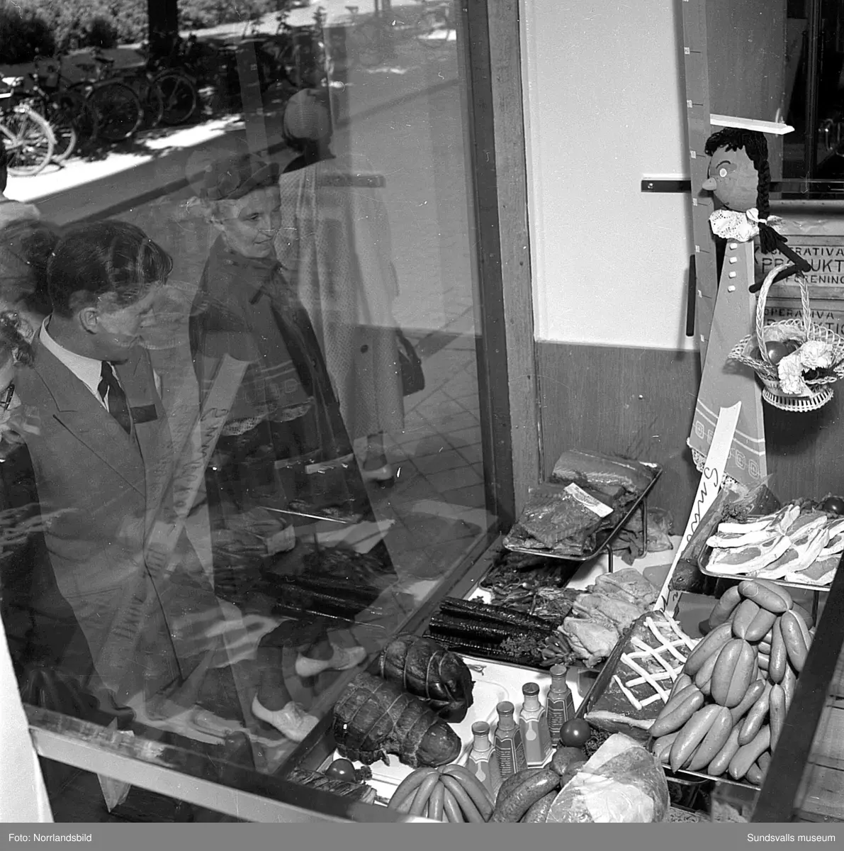 Konsums snabbköp vid Bankgatan har byggts ut 1952 och en kund är sångerskan Alice Babs som inspekterar fruktavdelningen och handlar för fem kronor och femtiosju öre.