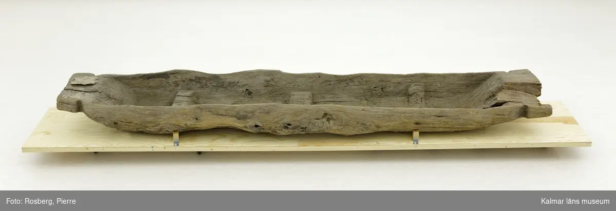 KLM 45113. Båt, stockbåt. Av stor urholkad trädstam, krokig med många knaggar. Huggen i ett stycke. Stamrunt tvärsnitt med runt fallande överhäng. Har tre kraftiga tofter eller skott utsparade i stocken. Går ej att urskilja för respektive akter, eventuellt är den något smalare änden fören. Rektangulära och rakt avskurna stävnockar, på den ena två stycken tamphål. På båtens ena långsida finns fyra stycken relingshål, på den andra sidan ett. På båten fastsatta pappersfragment, tre stycken, med information om båten och dess härkomst, till stor del oläsligt.