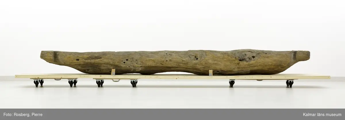 KLM 45113. Båt, stockbåt. Av stor urholkad trädstam, krokig med många knaggar. Huggen i ett stycke. Stamrunt tvärsnitt med runt fallande överhäng. Har tre kraftiga tofter eller skott utsparade i stocken. Går ej att urskilja för respektive akter, eventuellt är den något smalare änden fören. Rektangulära och rakt avskurna stävnockar, på den ena två stycken tamphål. På båtens ena långsida finns fyra stycken relingshål, på den andra sidan ett. På båten fastsatta pappersfragment, tre stycken, med information om båten och dess härkomst, till stor del oläsligt.