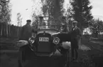 Fyra personer vid en bil.
Familjen Pettersson: Anders Johan Pettersson (givarens farfar), Harald Pettersson (givarens pappa), Martin Pettersson (givarens farbror). 
Bilen är en Overland Four som ägdes av skräddaremästare A. J. Pettersson, Lindesberg. Den hade registreringsnummer T2016 och registrerades den 25:e april 1923 med honom som ägare. År 1930 finns bilen kvar i bilregistret, men ägs numera av Viktor Teodor Johansson, Bofors.